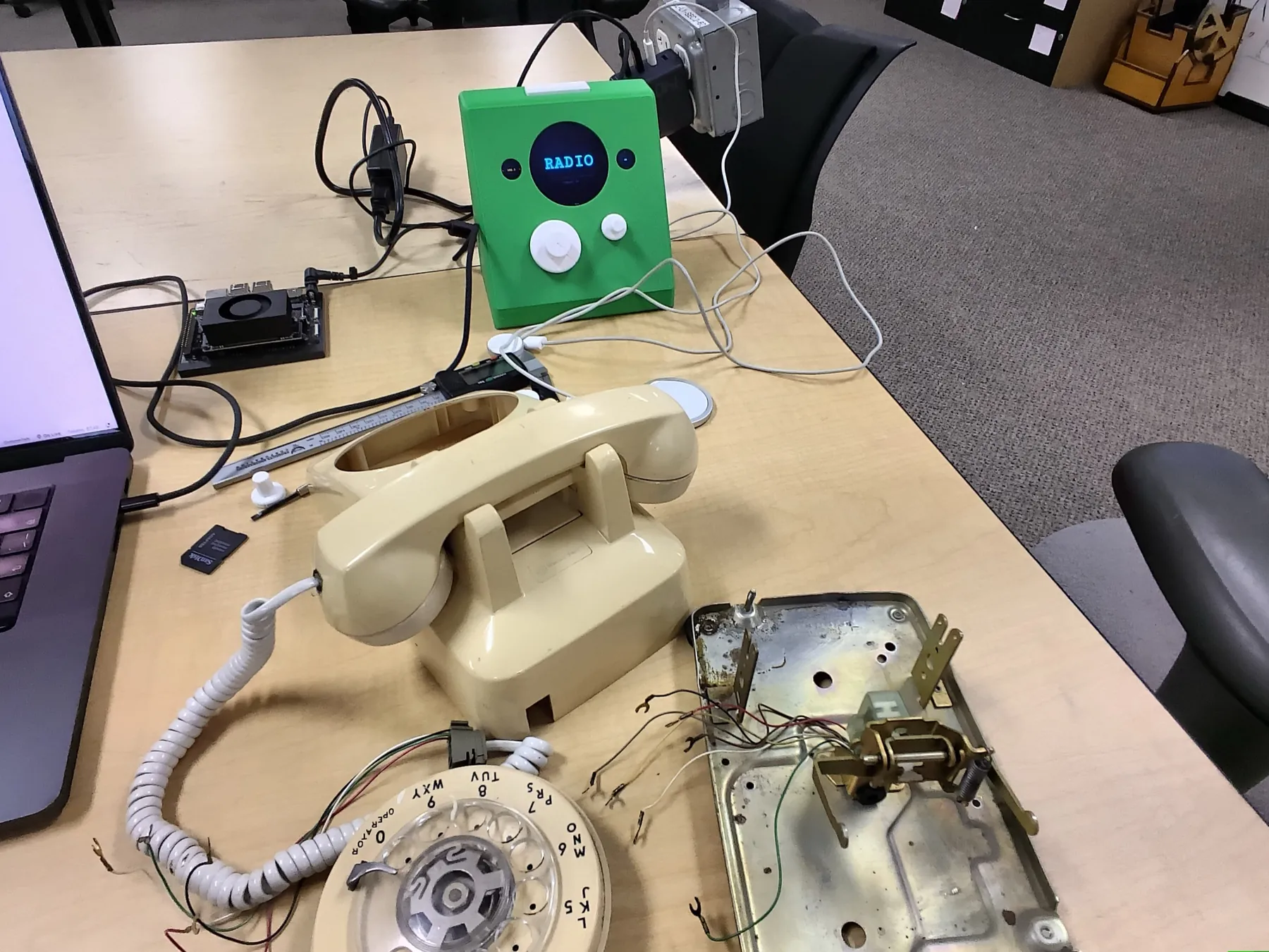 A cream Western Electric telephone on a workshop table with its dial and metal base plate removed