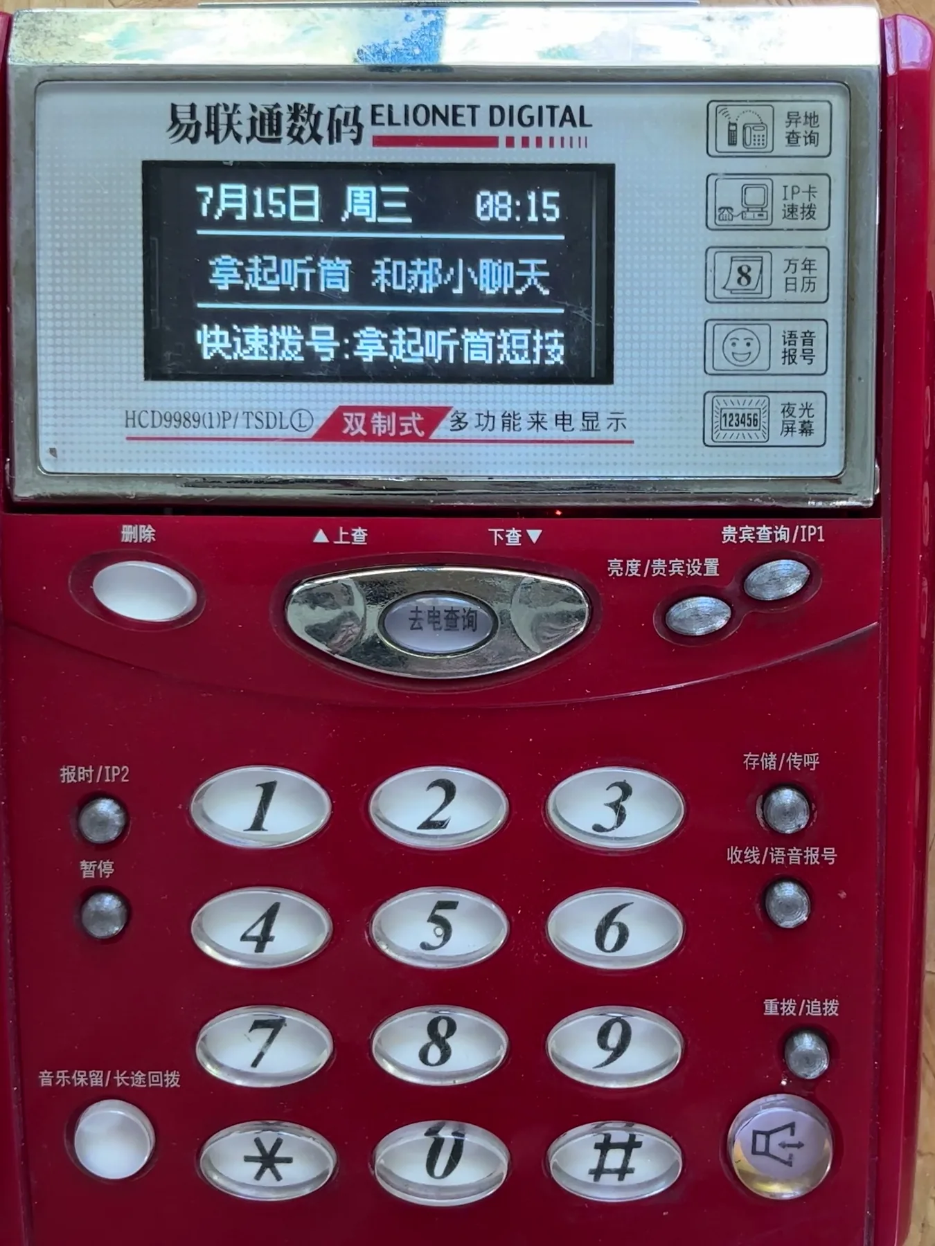 The finished red telephone from above: a small lit display in the old screen window shows the date and a line of Chinese text, above the number keys